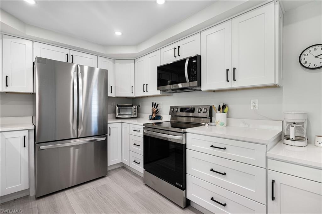 Kitchen featuring white cabinets, stainless steel appliances, and light hardwood / wood-style floors