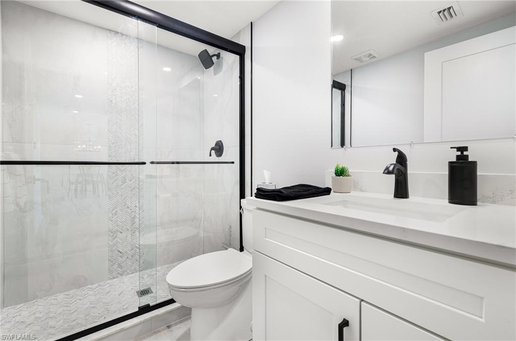 Bathroom with toilet, vanity, and a shower with door