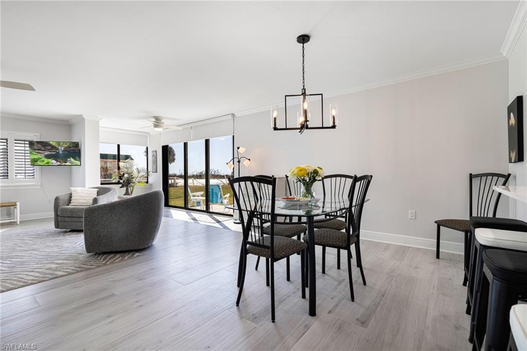 Dining room featuring crown molding, ceiling fan with notable chandelier, and light wood-type flooring