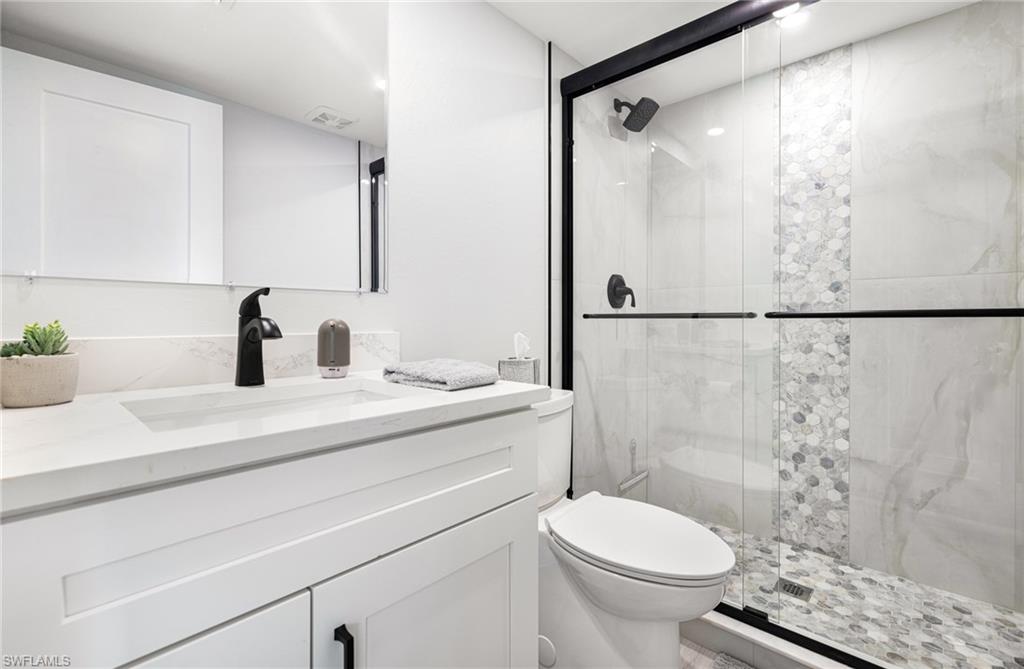 Bathroom featuring vanity, toilet, and an enclosed shower