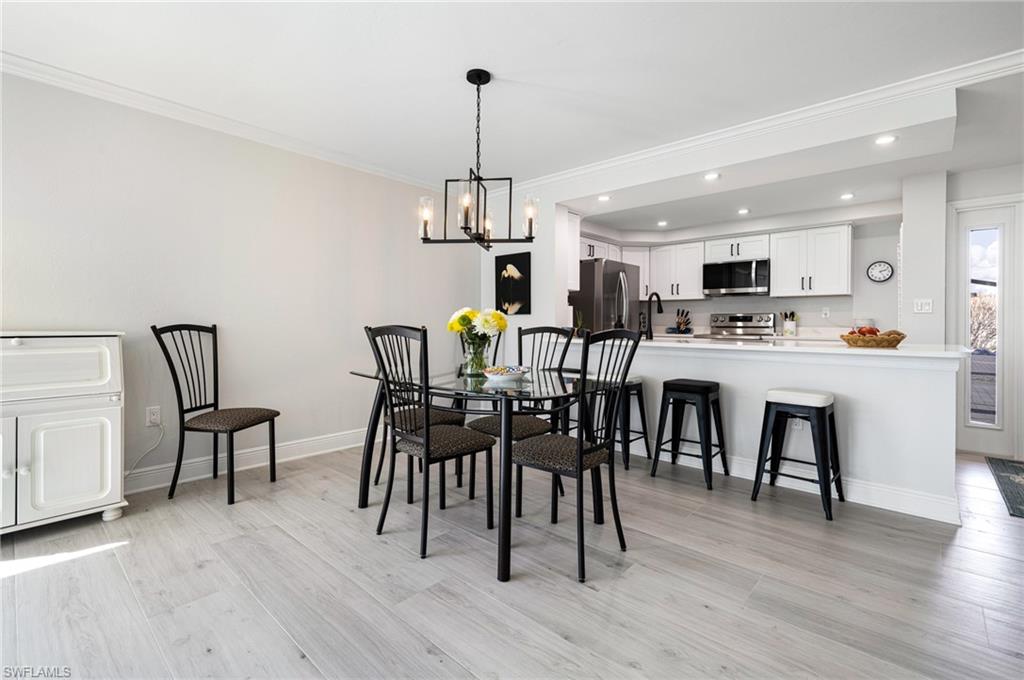 Dining room with an inviting chandelier, light hardwood / wood-style flooring, and ornamental molding