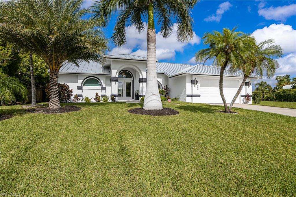 White stucco exterior with a metal roof and an arched entry