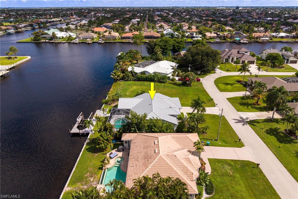 Canal-front property with a gray metal roof, screened pool enclosure, and private boat dock