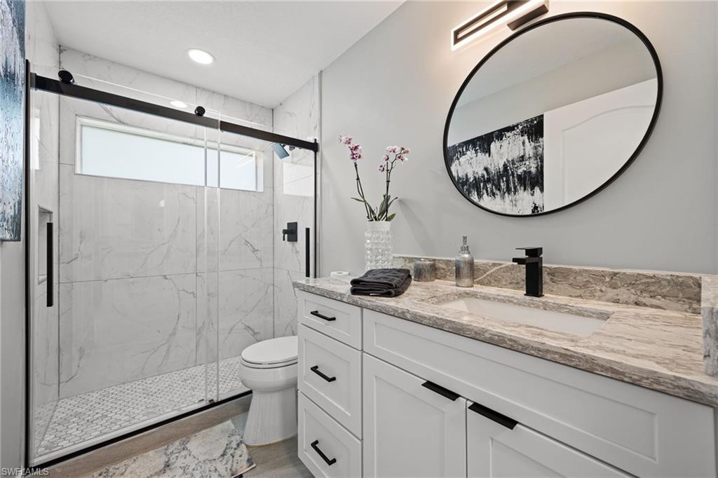 Walk-in shower with a glass enclosure, white tile surround, and an integrated window