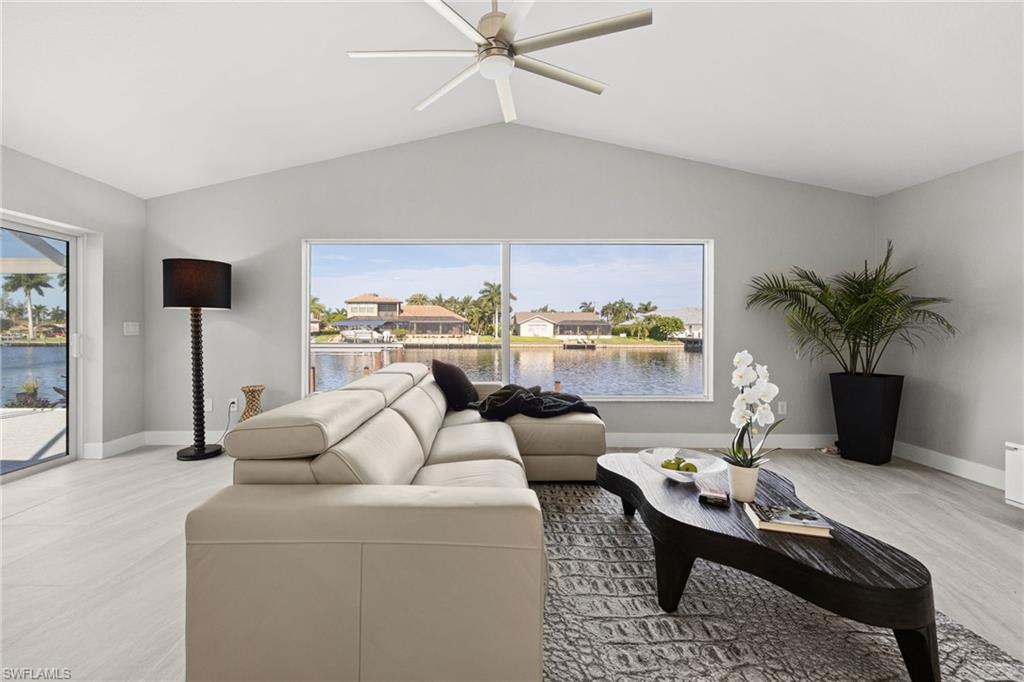 Vaulted ceilings, a contemporary ceiling fan, and large windows with water frontage define this living space