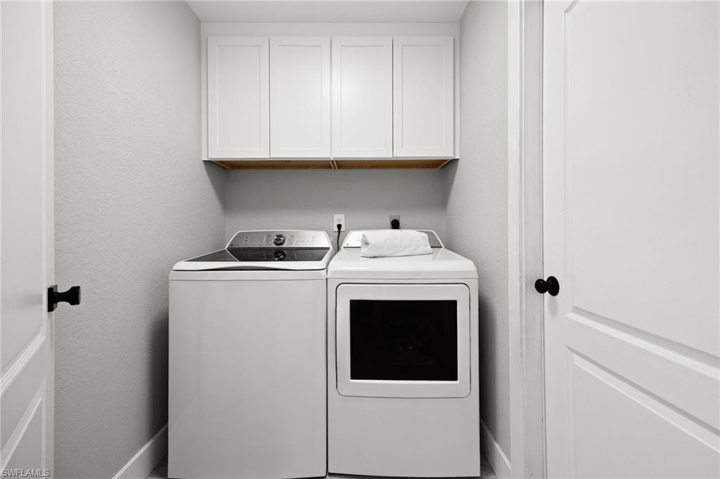 Laundry area featuring white cabinetry with a wood-finish shelf