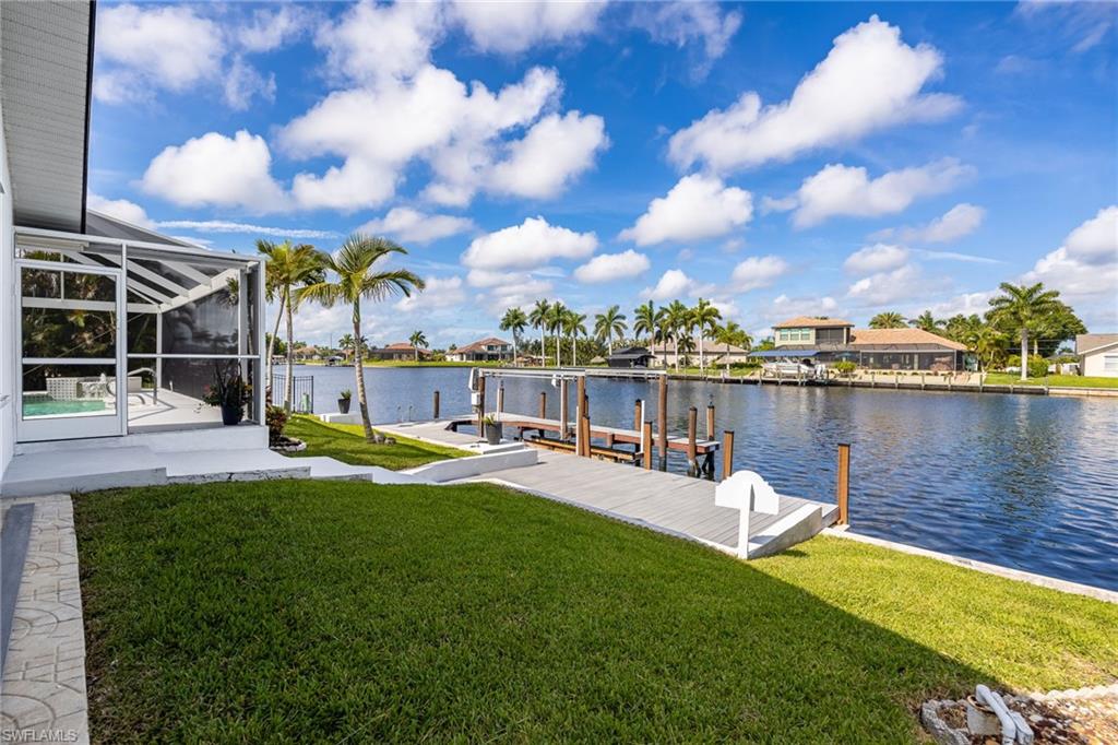 Waterfront property featuring a private dock, screened-in patio, and manicured lawn