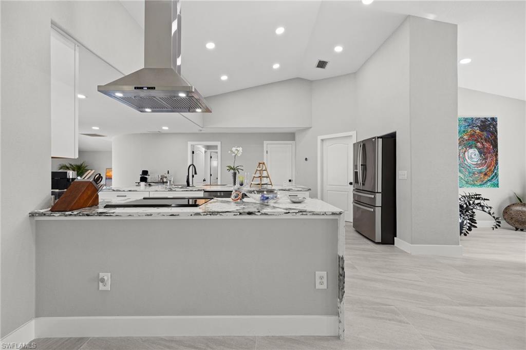 Spacious kitchen featuring a large island, stainless steel range hood, recessed lighting, and light-toned tile flooring