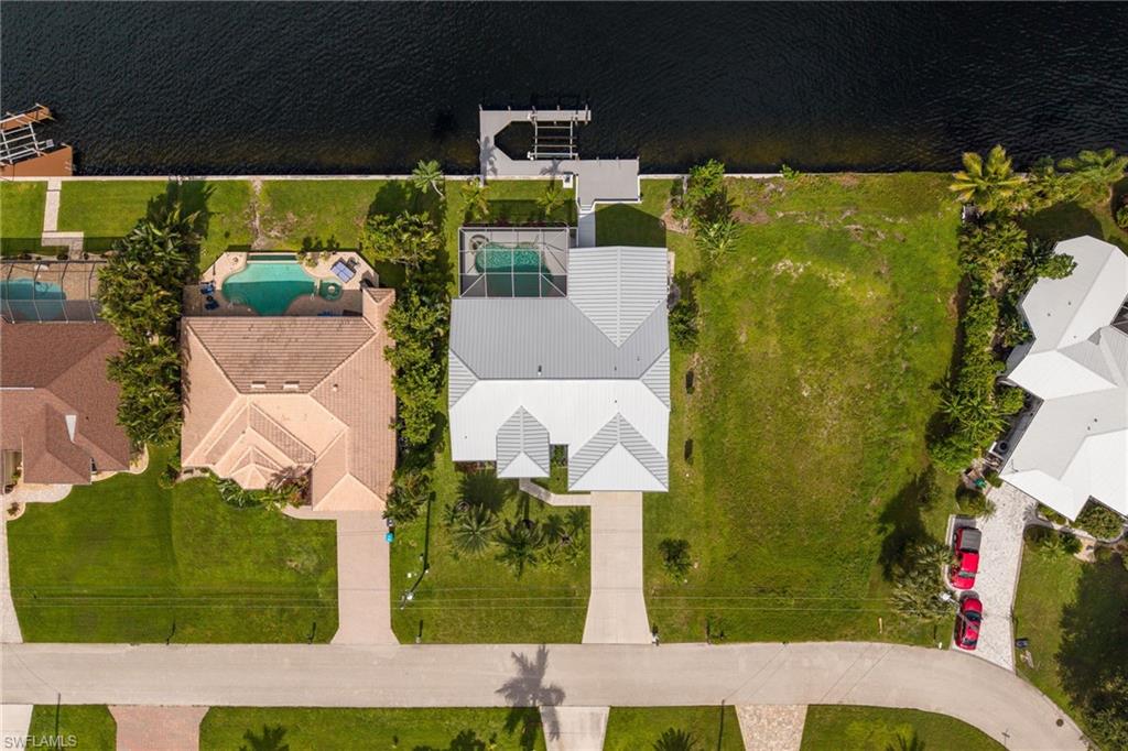 Waterfront property featuring a private boat dock, concrete seawall, and a spacious green lawn