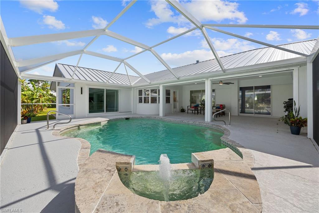 Screened-in pool deck featuring a built-in spa with water feature, curved swimming pool, and multiple sliding glass doors to the interior