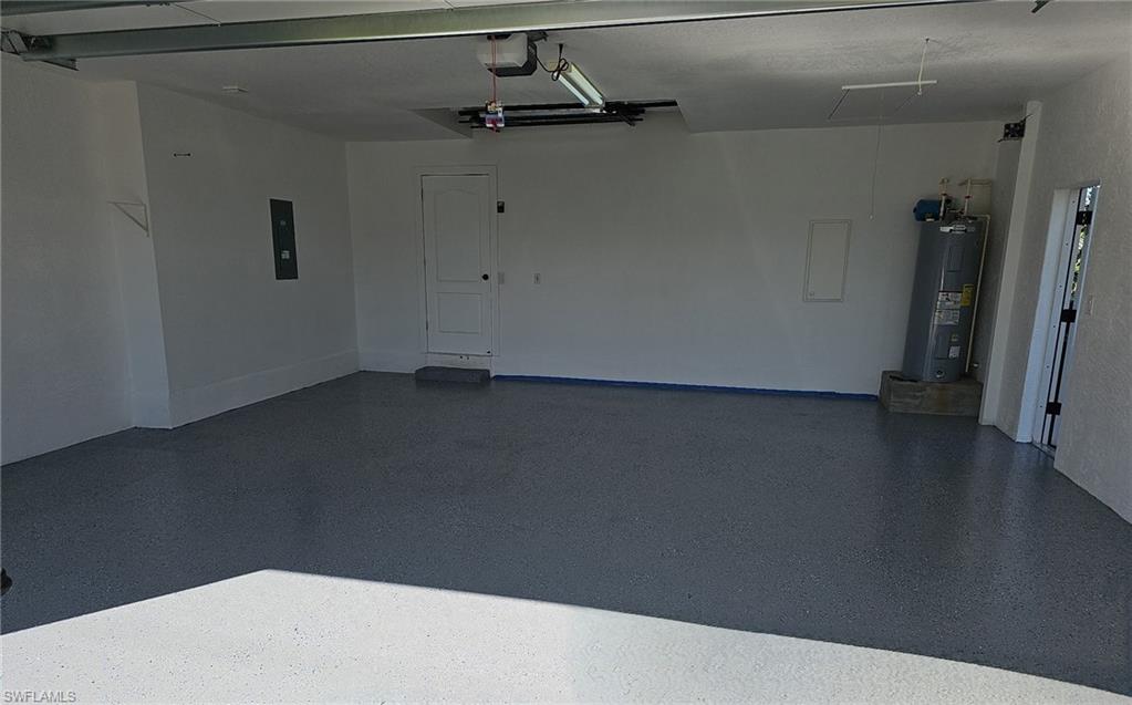 Garage with electric panel, electric water heater, and a garage door opener
