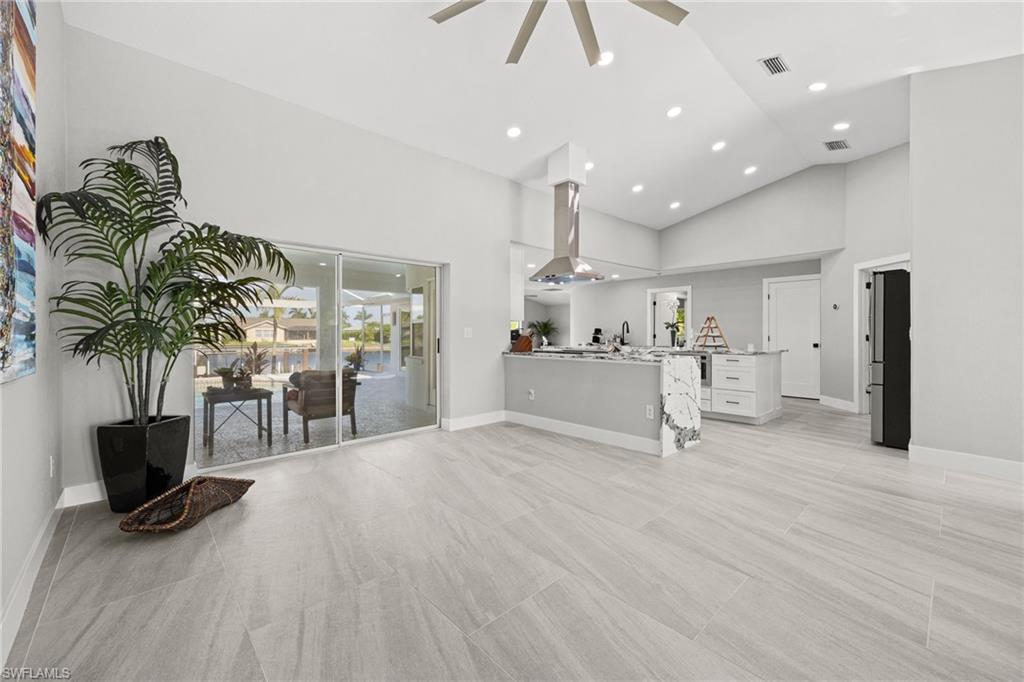 Spacious living area with vaulted ceilings, recessed lighting, and large format tile flooring