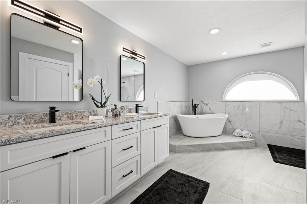 Dual vanity with stone-finish countertops, undermount sinks, and matte black fixtures