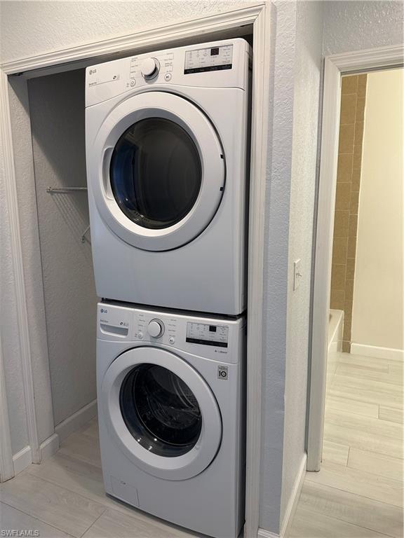 Laundry room featuring stacked washer / drying machine and light wood-type flooring