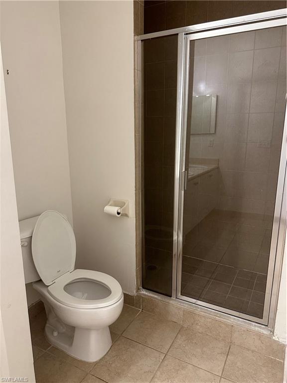 Bathroom with toilet, tile patterned floors, and a shower with door