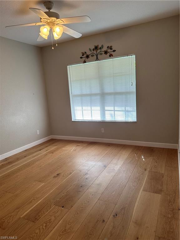 Empty room with ceiling fan and light hardwood / wood-style flooring