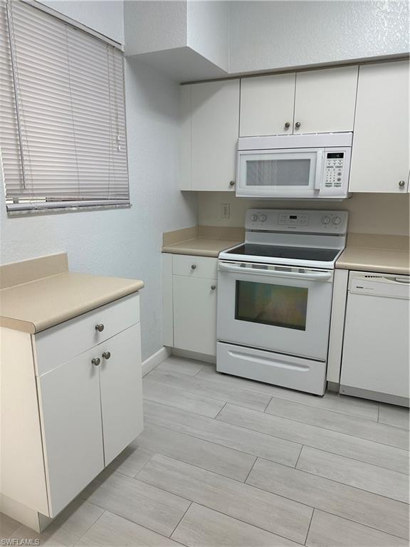 Kitchen featuring white cabinetry, white range oven, and dishwasher