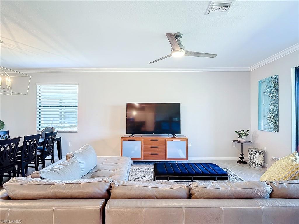 Living room with ornamental molding and ceiling fan with notable chandelier
