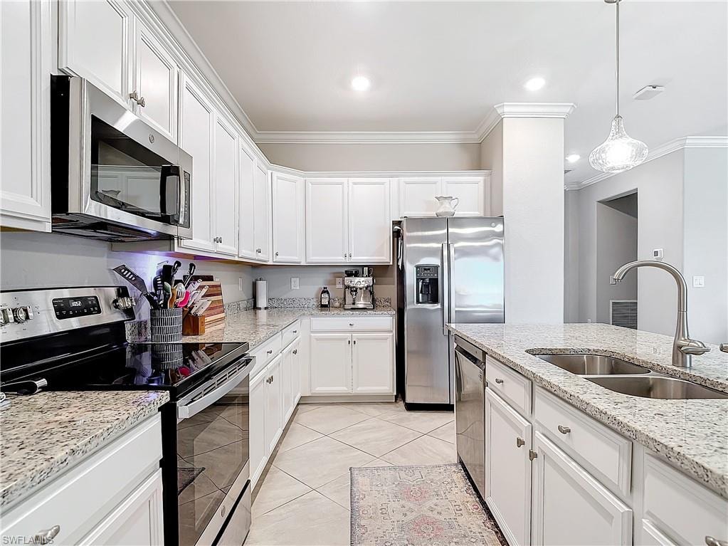 Kitchen featuring white cabinets, appliances with stainless steel finishes, sink, and crown molding