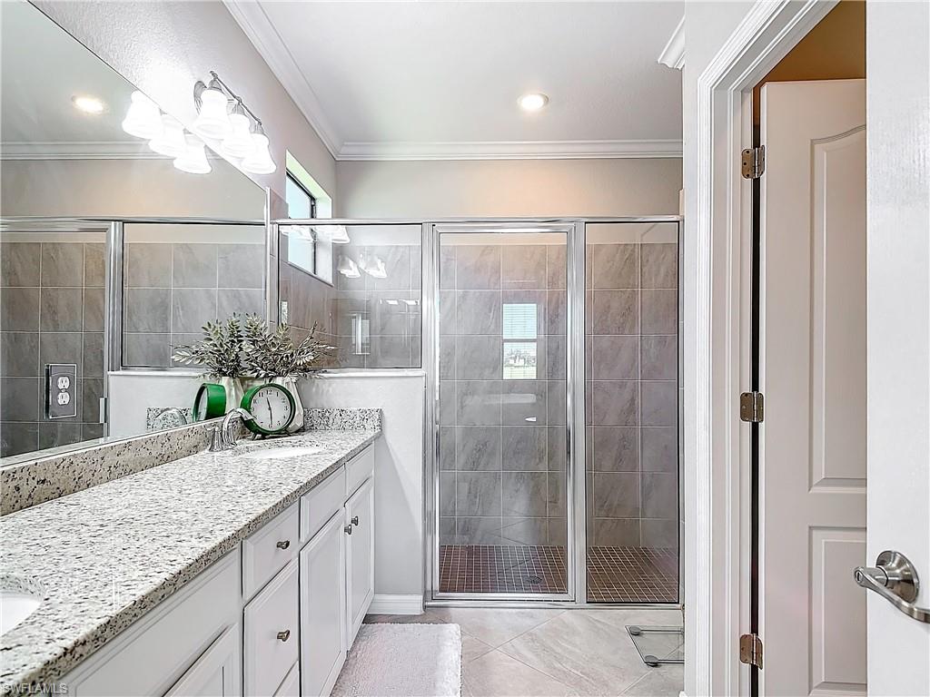 Bathroom with an enclosed shower, vanity, and crown molding