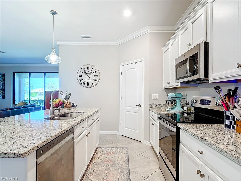 Kitchen featuring white cabinetry, appliances with stainless steel finishes, sink, and a center island with sink