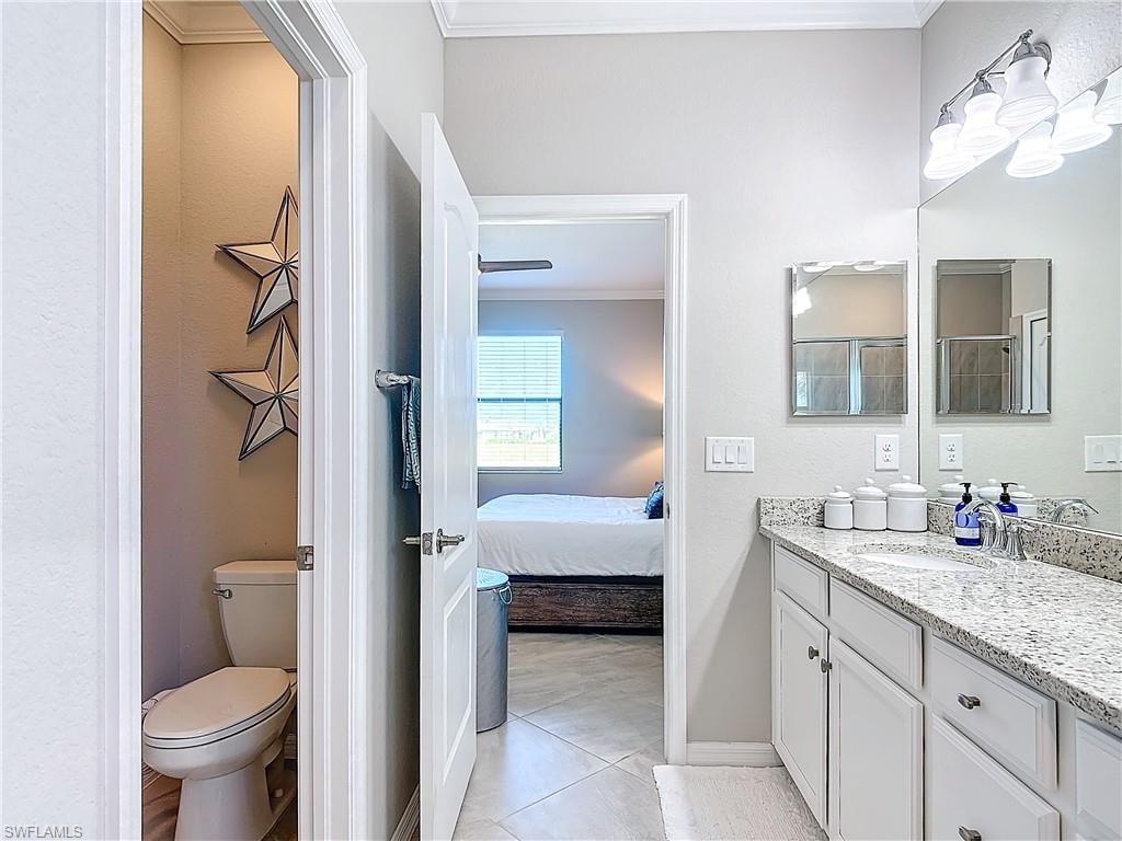 Bathroom featuring toilet, vanity, tile patterned floors, and crown molding