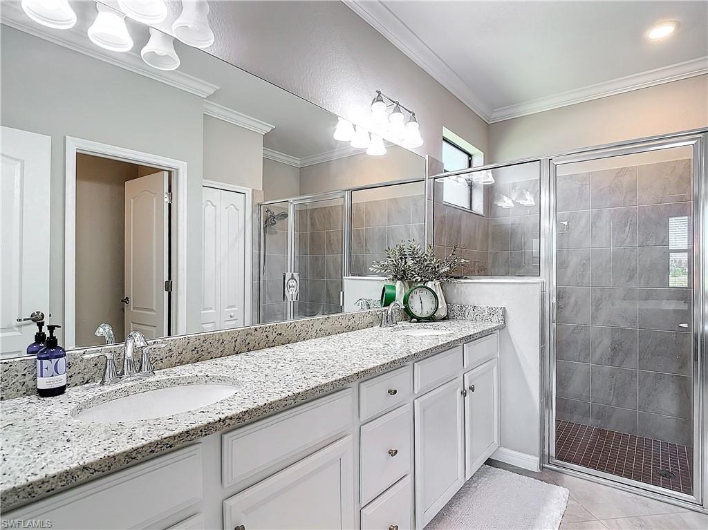 Bathroom with vanity, tile patterned floors, an enclosed shower, and ornamental molding