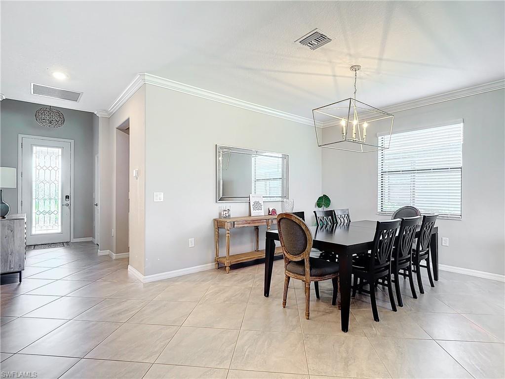 Tiled dining area with an inviting chandelier and crown molding