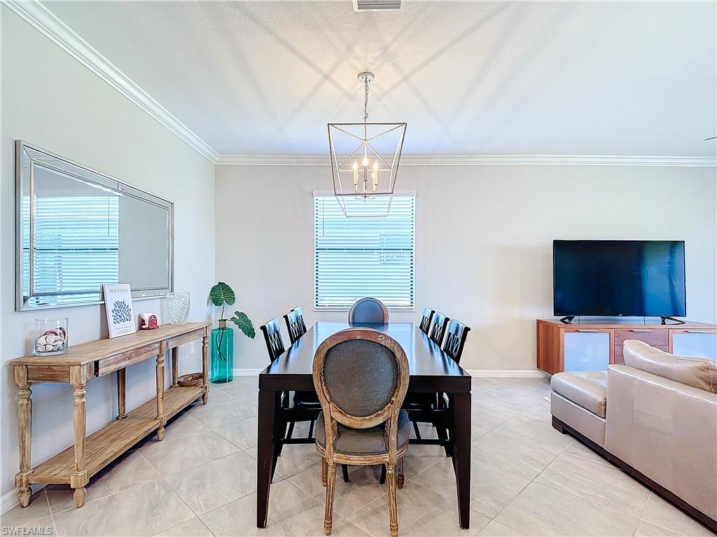 Tiled dining area featuring ornamental molding and a chandelier