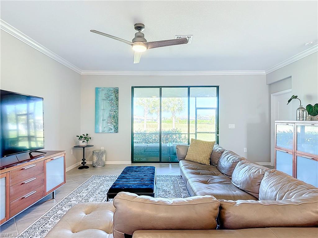Tiled living room with ceiling fan and ornamental molding