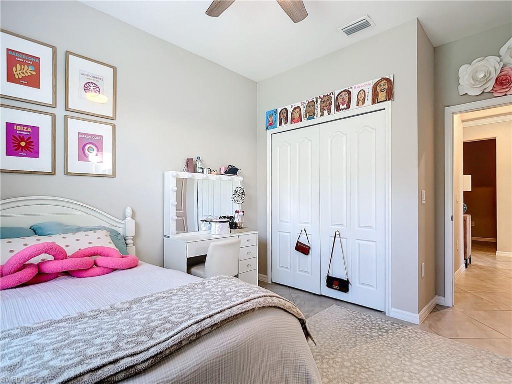 Tiled bedroom with ceiling fan and a closet