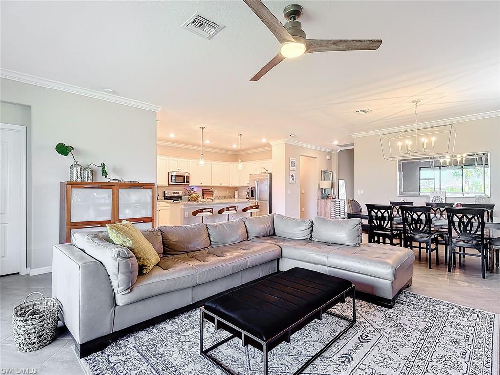Living room with ceiling fan with notable chandelier and crown molding