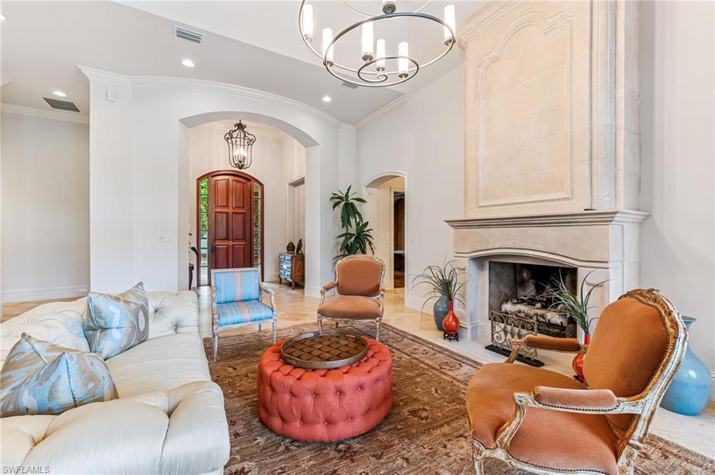Living room with light hardwood / wood-style flooring, crown molding, a high end fireplace, and a chandelier