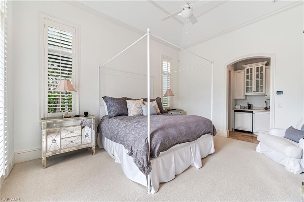 Bedroom with light colored carpet, multiple windows, and ceiling fan