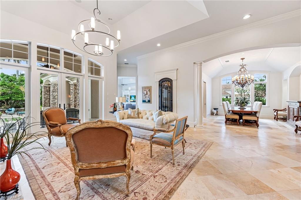 Living room featuring lofted ceiling, ornate columns, french doors, and a chandelier