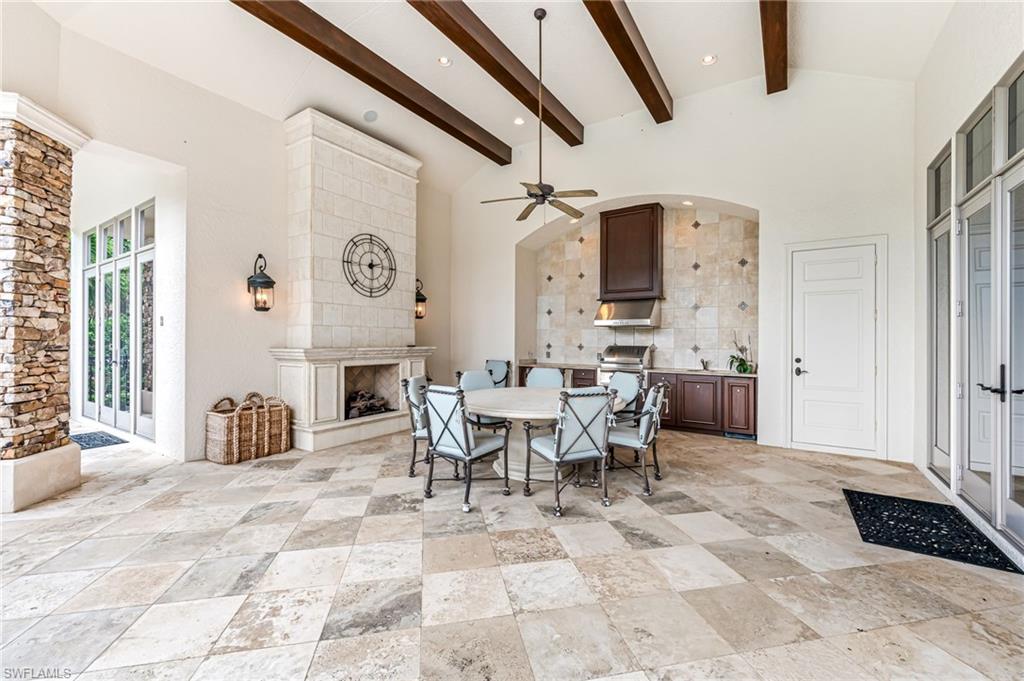 Dining space with ceiling fan, beam ceiling, a fireplace, and high vaulted ceiling