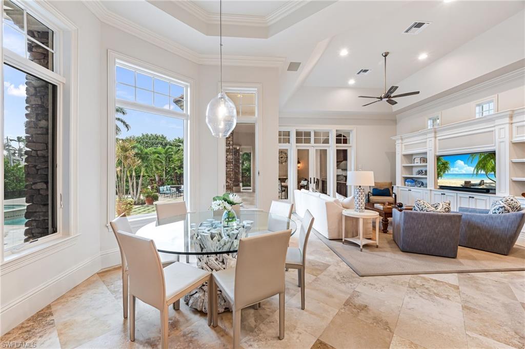 Dining space with ceiling fan, a raised ceiling, crown molding, and french doors