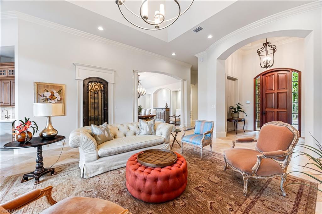 Living room with crown molding and a notable chandelier