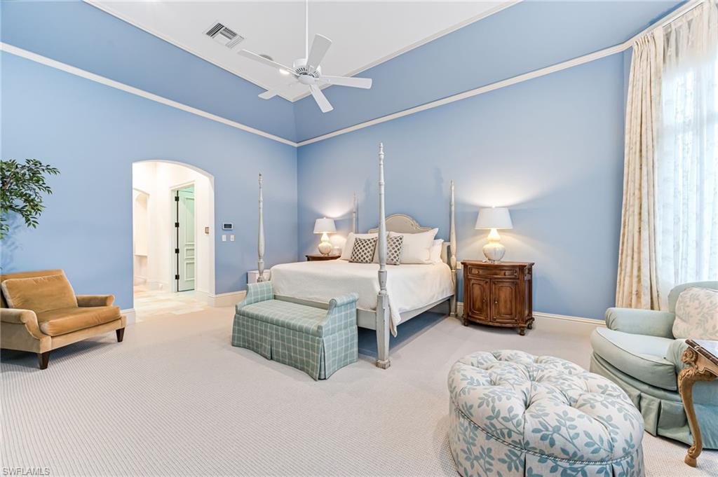 Bedroom featuring multiple windows, ceiling fan, light carpet, and a high ceiling
