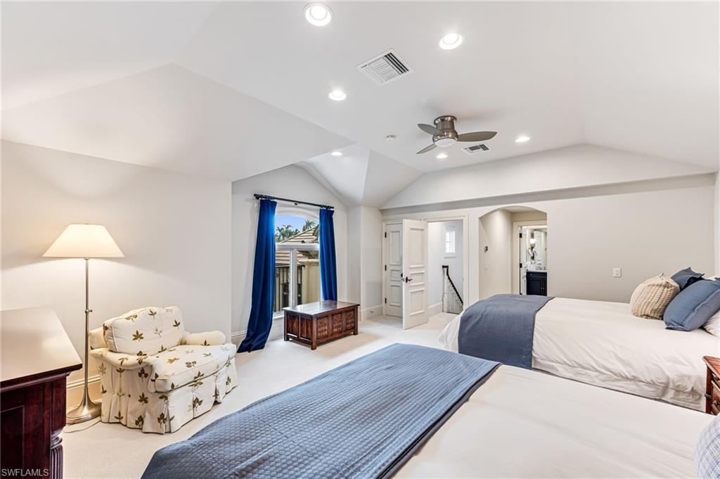 Carpeted bedroom with ceiling fan and lofted ceiling