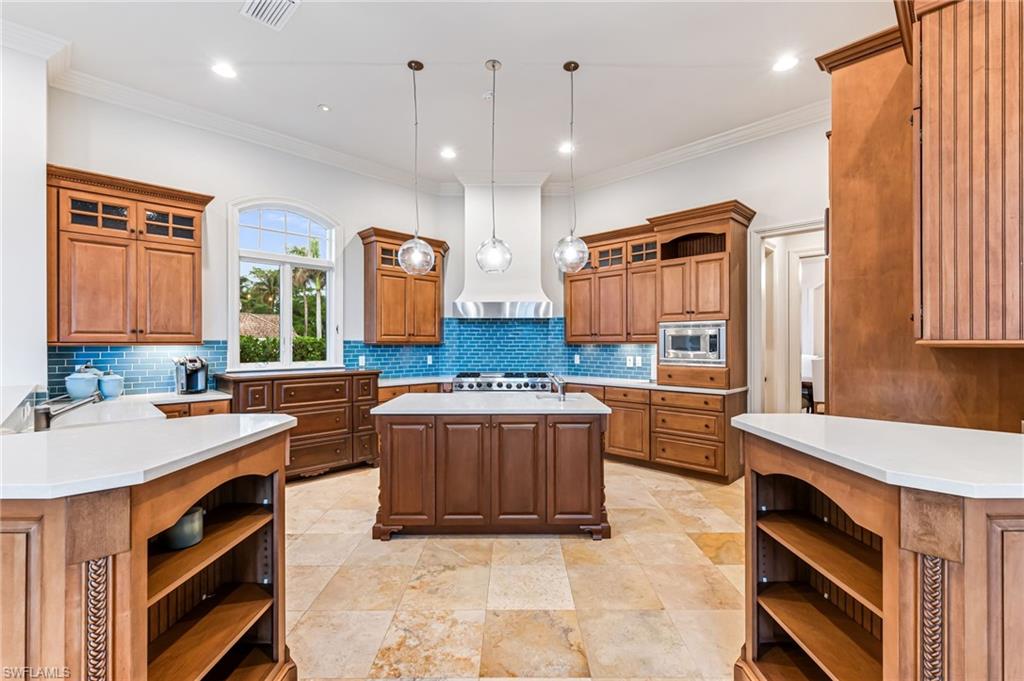 Kitchen with pendant lighting, a center island, stainless steel appliances, and tasteful backsplash
