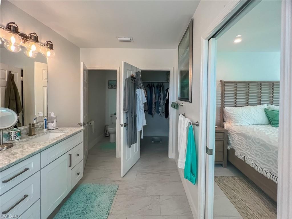 Bedroom with connected bathroom, light wood-type flooring, and ceiling fan