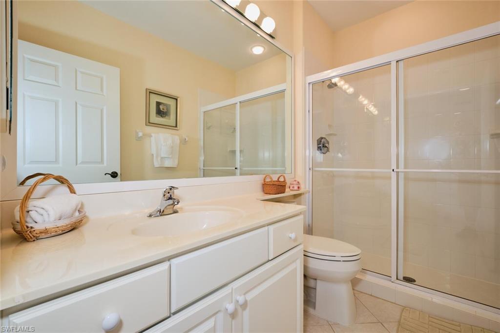 Bathroom featuring vanity, tile patterned flooring, toilet, and an enclosed shower