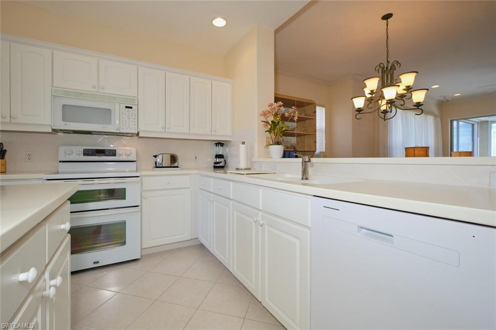 Kitchen featuring white cabinetry, decorative light fixtures, white appliances, and an inviting chandelier