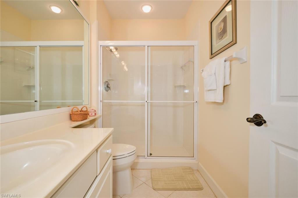 Bathroom with vanity, a shower with door, tile patterned flooring, and toilet