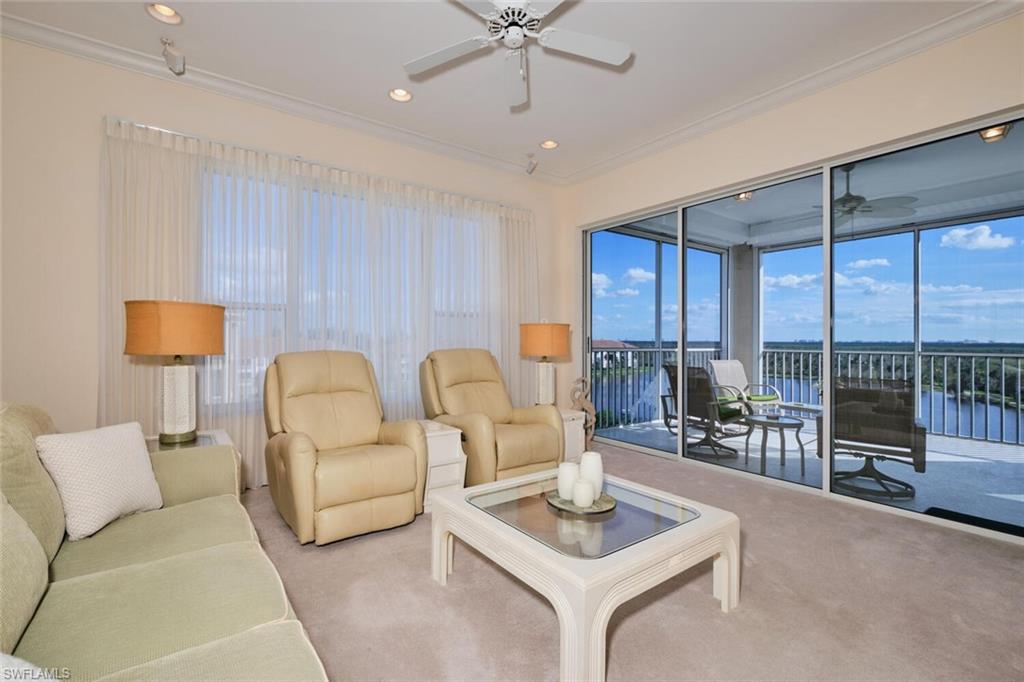 Living room with ornamental molding, a wealth of natural light, a water view, and light colored carpet