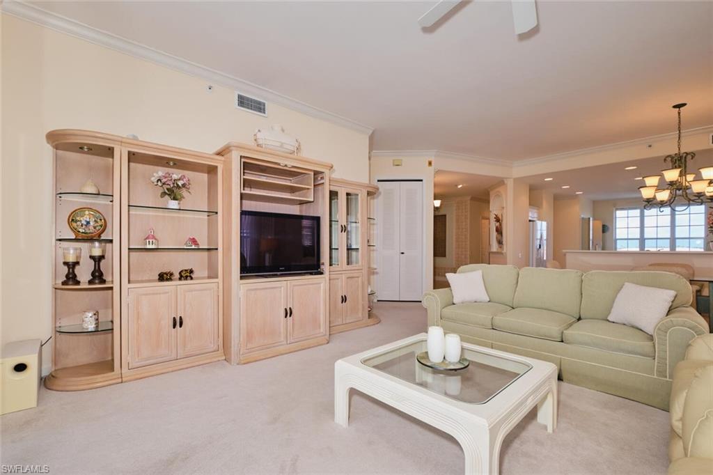 Carpeted living room featuring ceiling fan with notable chandelier and crown molding
