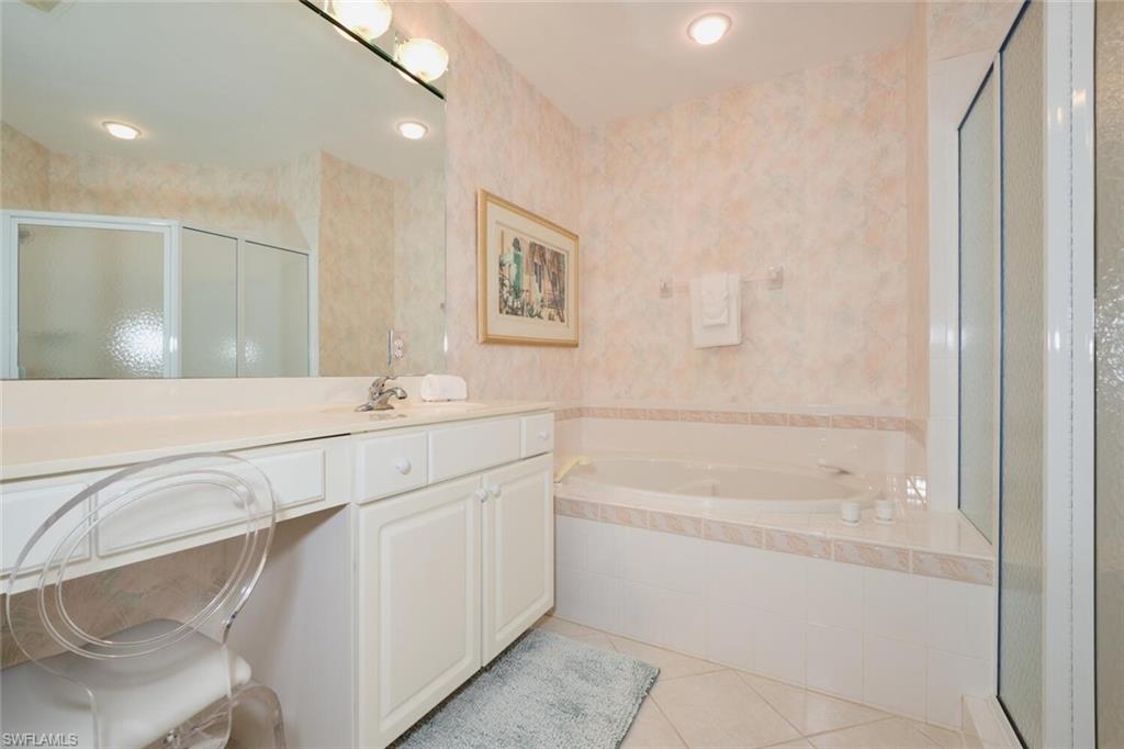 Bathroom featuring vanity, shower with separate bathtub, and tile patterned flooring
