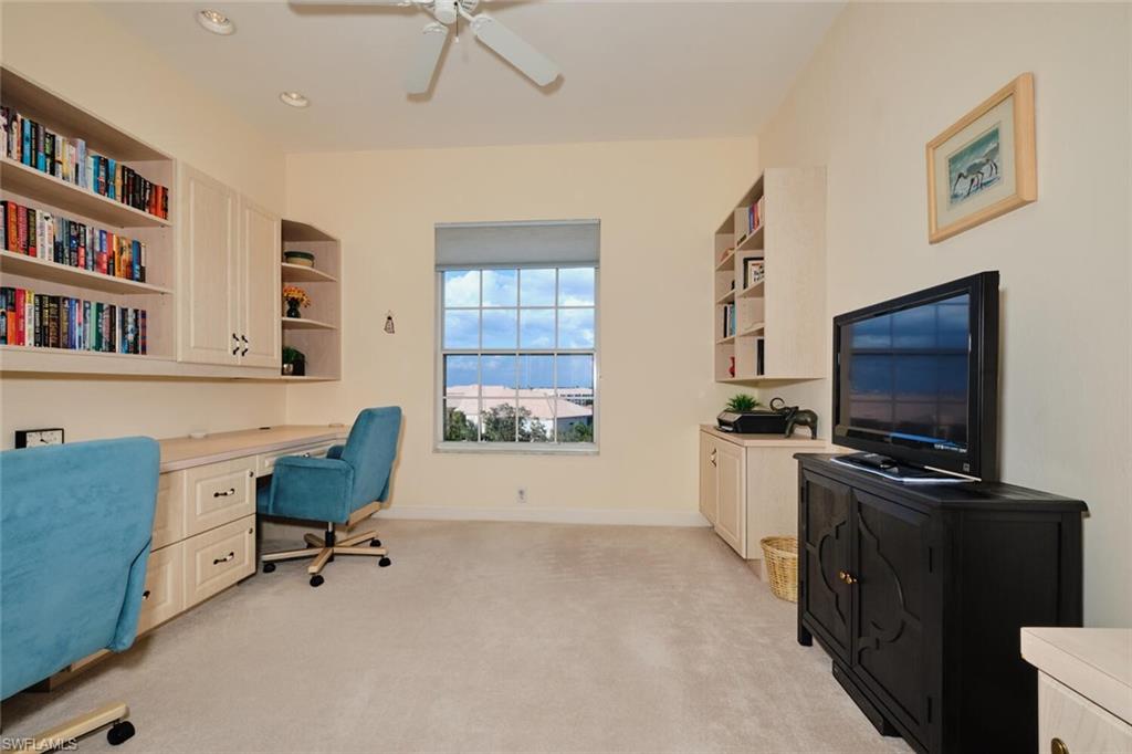 Office space with light colored carpet, built in desk, and ceiling fan