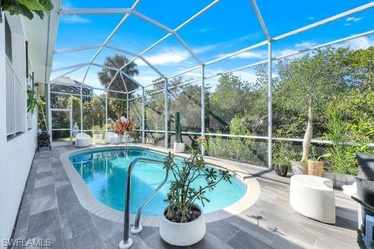 View of swimming pool featuring a lanai and a patio area